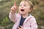 happy-little-girl-pointing-up-while-smiling-outdoors_138670-3995[1].webp