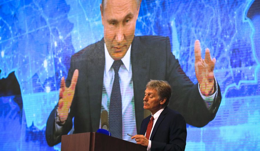 Kremlin spokesman Dmitry Peskov, bottom, looks on as Russian President Vladimir Putin speaks via video call during a news conference in Moscow, Russia, Thursday, Dec. 17, 2020. (AP Photo/Alexander Zemlianichenko)